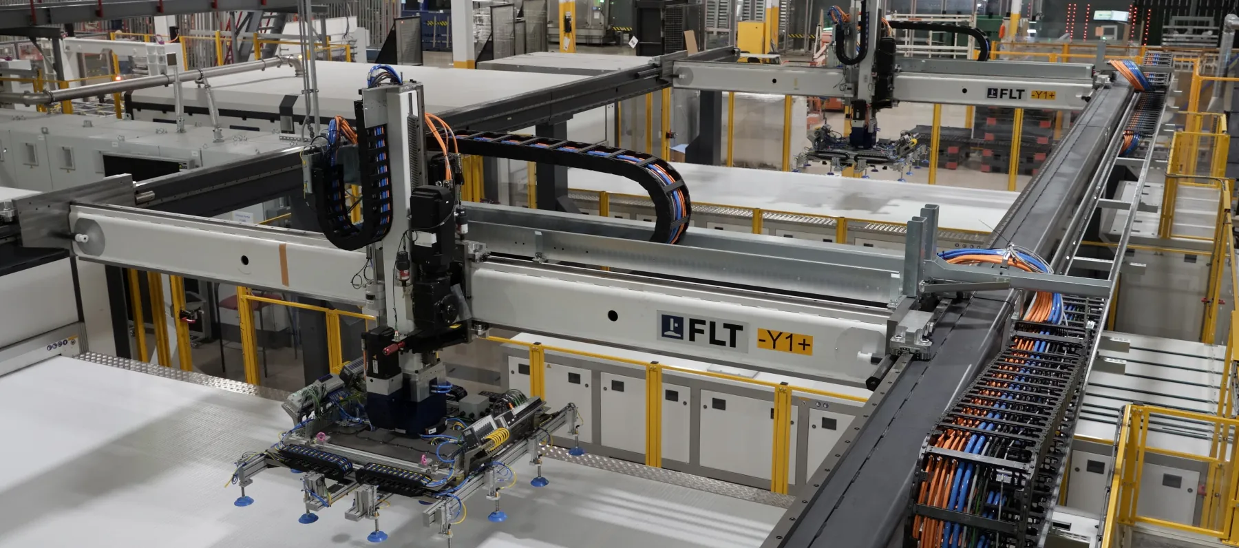 An automated gantry lifting a glass sheet by vacuum cups on a Cardinal production line