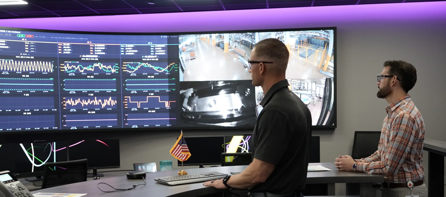 Two Cardinal specialists reviewing live line data and plant camera feeds on the control-room video wall